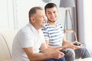 Fototapeta premium Mature man playing video game with his son at home