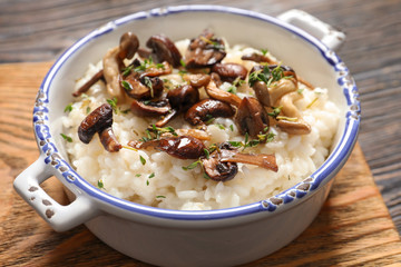 Dish with risotto and mushrooms on wooden board