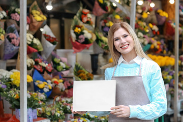 Business owner holding blank paper near her store with flowers