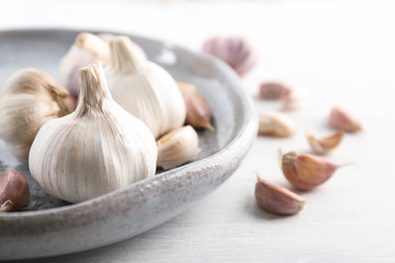 Plate with fresh garlic on table