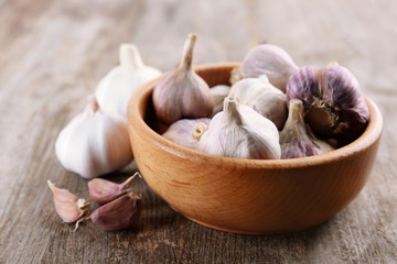 Bowl with fresh garlic on wooden table
