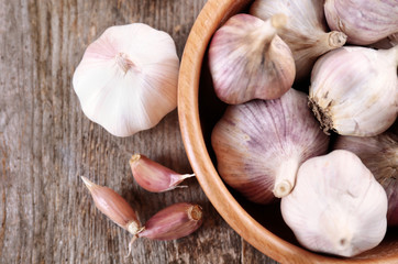 Bowl with fresh garlic on wooden table