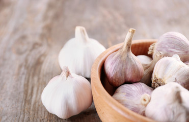 Bowl with fresh garlic on wooden table