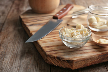 Bowl with chopped garlic on wooden board