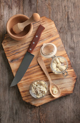 Bowl with chopped garlic and cloves in jar on wooden board