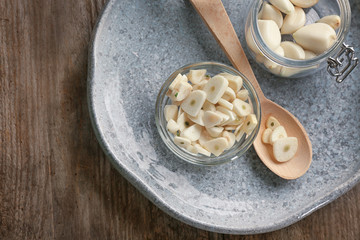 Bowl with chopped garlic and cloves in jar on plate