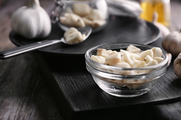 Bowl with chopped garlic on wooden board