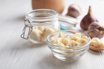 Bowl with chopped garlic and cloves in jar on wooden table