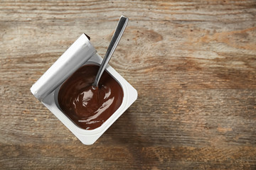 Plastic cup with chocolate yogurt on wooden background