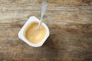 Plastic cup with yogurt on wooden background