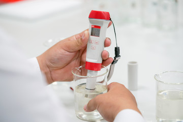 The scientist work at the chemical solution with handle pH meter