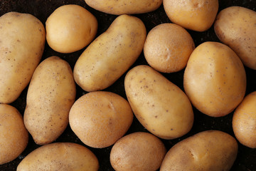 Fresh raw potatoes on ground, top view