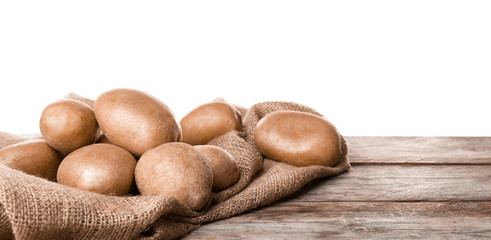 Fresh raw potatoes on wooden table against white background