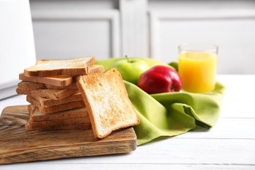 Wooden board with tasty toasted bread on table