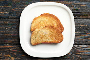 Plate with tasty toasted bread on wooden table