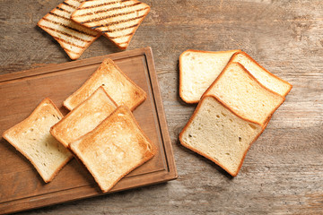 Wooden board with tasty toasted bread on table