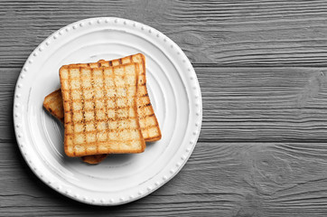 Plate with tasty toasted bread on wooden table