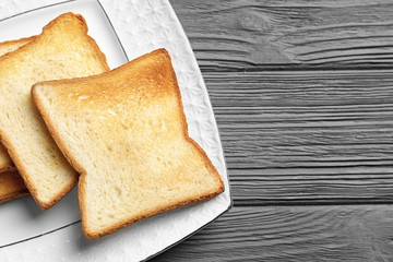Plate with tasty toasted bread on wooden table
