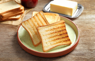 Plate with tasty toasted bread on wooden table