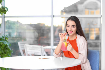 Young woman with mason jar of pink lemonade in cafe