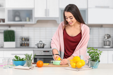Obraz na płótnie Canvas Young woman preparing tasty lemonade in kitchen