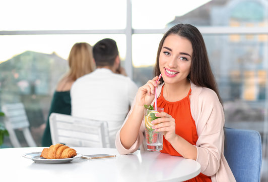 Young woman with glass of lemonade in cafe