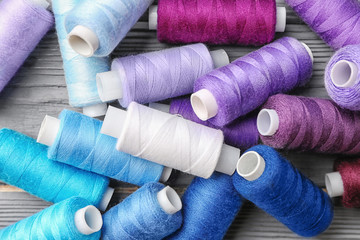Colorful sewing threads on wooden background, closeup