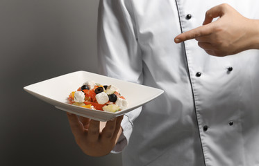 Male chef holding plate with dish, closeup