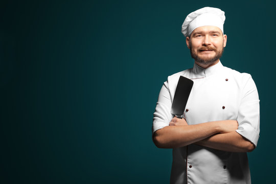Handsome male chef with knife on color background