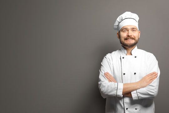 Handsome male chef on gray background