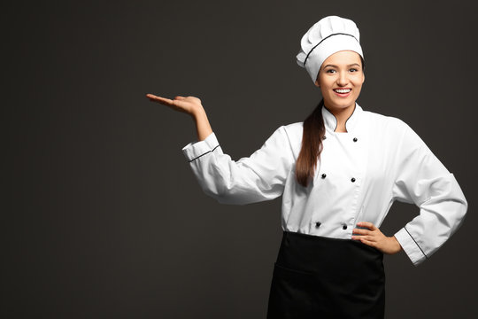 Beautiful female chef on dark background
