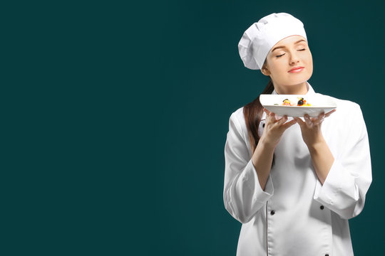 Beautiful female chef holding plate with dish on color background