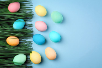 Fototapeta na wymiar Dyed Easter eggs and decorative grass on color background
