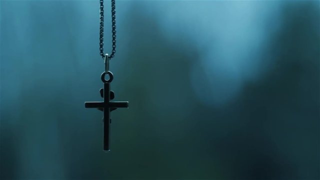 Christian crucifix pendant swinging on chain.
