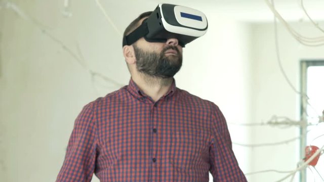 Young, male architect with vr goggle checking project at new home
