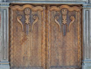 Isolated shot of beautifully, elaborately carved large wooden double doors, with a solid stone frame - 191125926