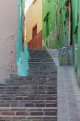 Steep brick steps leading up and through a very narrow passageway, with colorful houses on either side, in Guanajuato, Mexico - 191125953