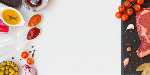 A fresh raw beef entrecote with ingredients to cooking tasty dinner with space for text. Top view.