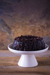 Chocolate bundt cake on a white cake stand. Rustic background 
