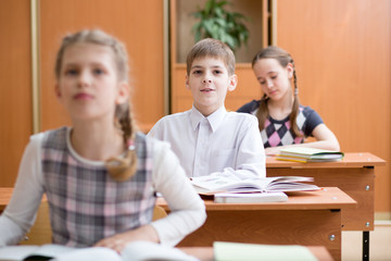Fototapeta premium education, elementary school, learning and people concept - group of school kids writing test in classroom