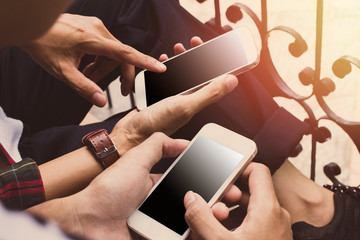 Close up of men and woman hands holding touching mobile phone with blank copy space for your text message in cafe with light Sunset,Vintage tone.Selective focus