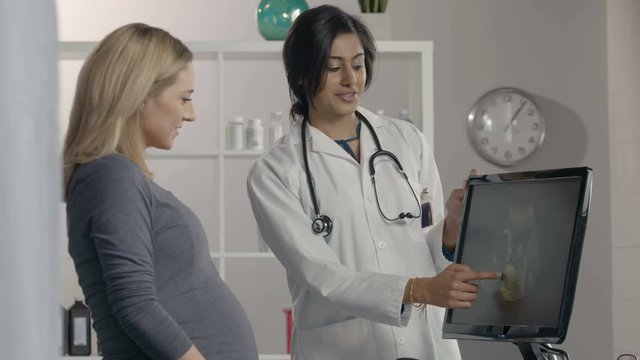 Female Doctor showing ultrasound image to pregnant patient