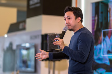 Closeup portrait of asian Speaker with casual suit on the stage over the presentation screen in the...