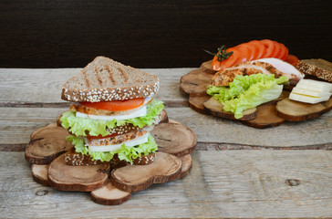 Sandwich of triangular bread with chicken breast tomato and cheese Wooden rustic background