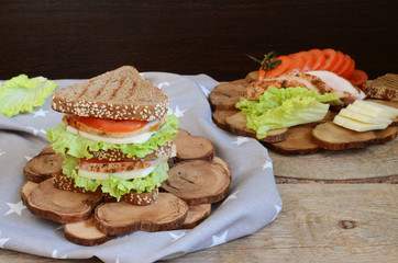 Sandwich of triangular bread with chicken breast tomato and cheese Wooden stand