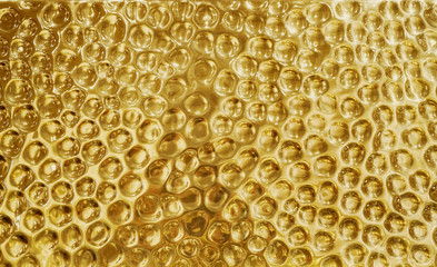 Gold shiny hammered metal background pattern with highlights and reflections from light. Circles impression on dimpled brass sheet metal surface.