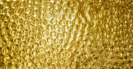 Gold shiny hammered metal background pattern with highlights and reflections from light. Circles impression on dimpled brass sheet metal surface.
