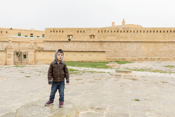 Fototapeta na wymiar Young boy playing in front of Saint Elmo fort, Valletta, Malta