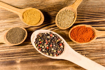 Spoons with the different spices on wooden table. Top view