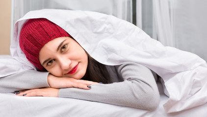 Young girl wearing knitted hat and suit sleeping in bed close up. Good morning.